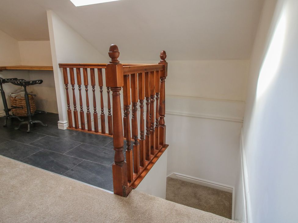 A staircase with a wooden railing in a hallway at Old Forge Apartment in Cookley