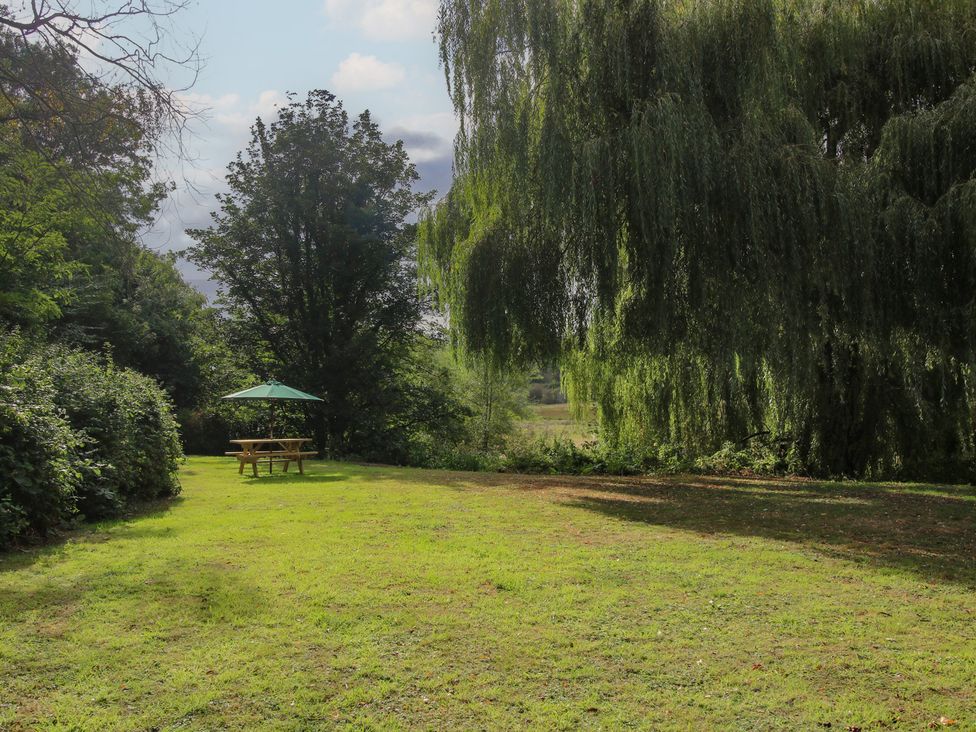 A garden with a picnic table and umbrella at Old Forge Apartment in Cookley