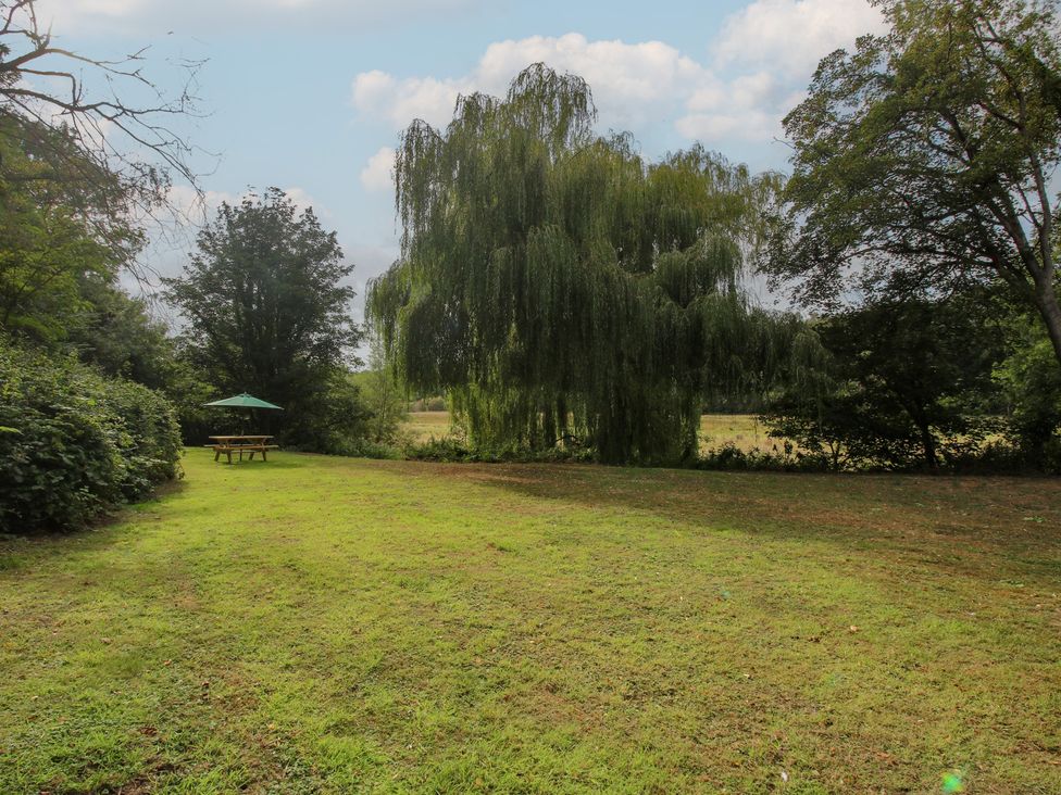 A garden with a table and umbrella near a tree at Old Forge Apartment in Cookley