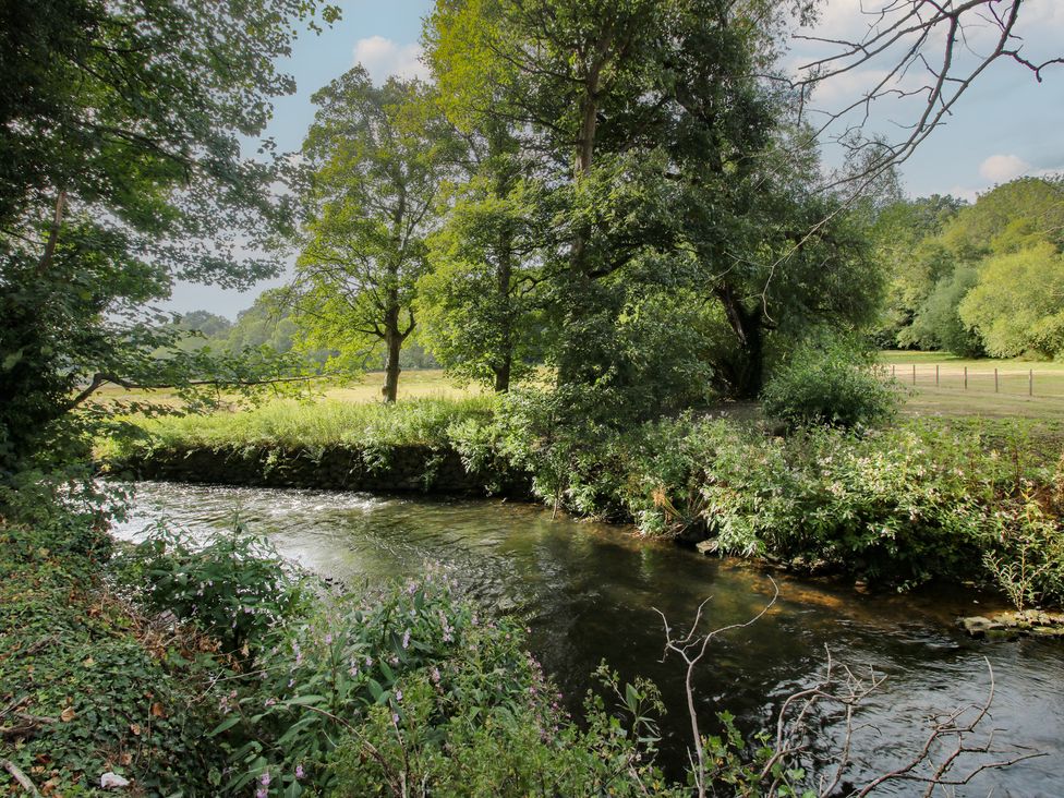 A river with trees and bushes along the bank at Old Forge Apartment Cookley