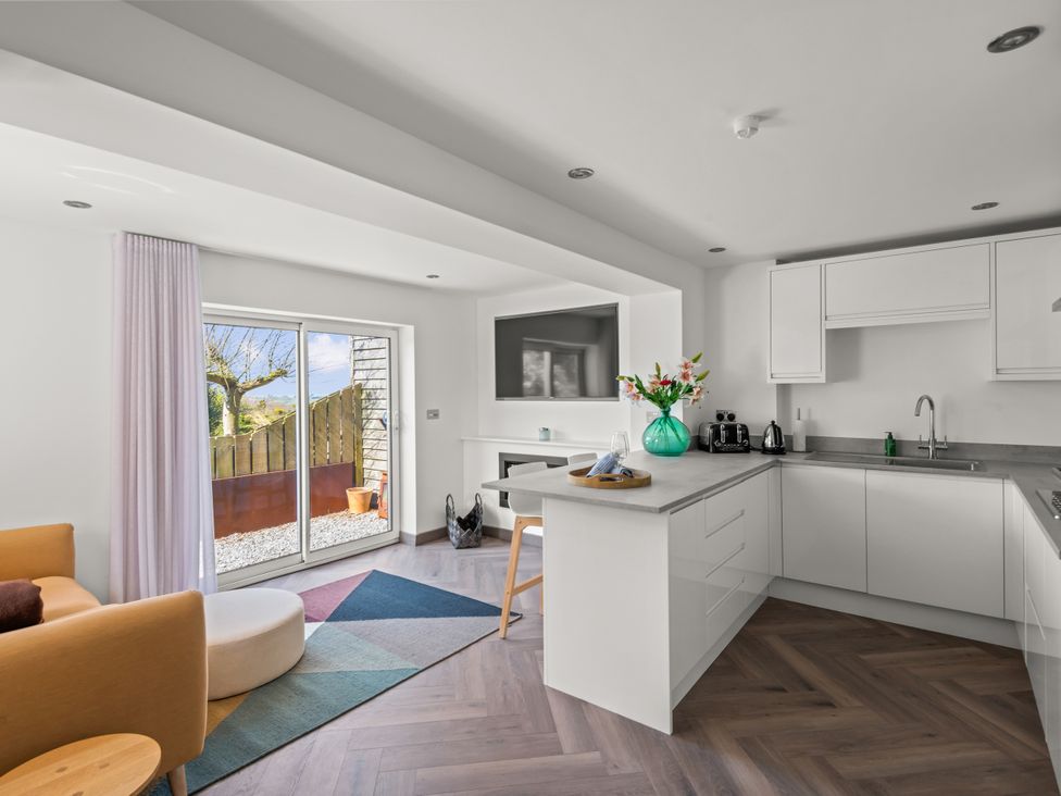 A kitchen with a sofa and a sliding door at Capton Snug in Capton near Dartmouth