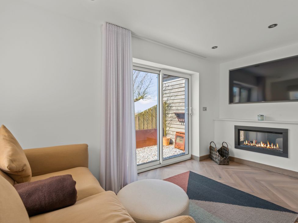 A snug with a sofa, television, and fireplace at Capton Snug in Capton near Dartmouth