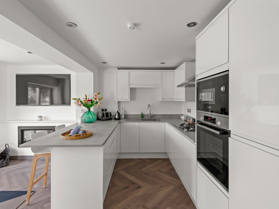 A kitchen with modern appliances and flowers on the countertop at Capton Snug near Dartmouth