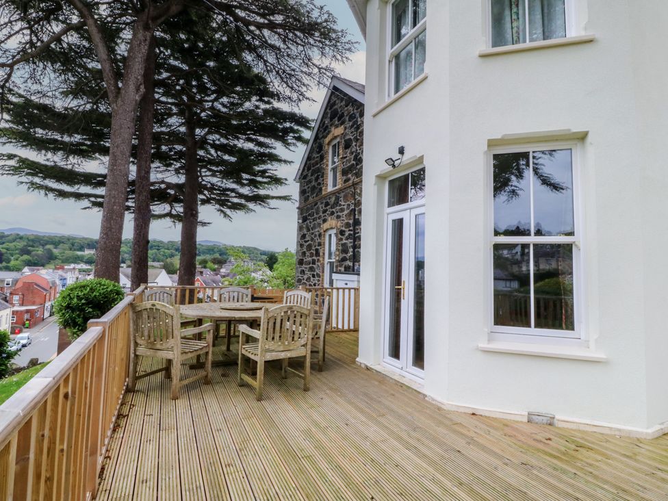 An outdoor area featuring a wooden deck with a table and chairs at Fir Grove in Menai Bridge