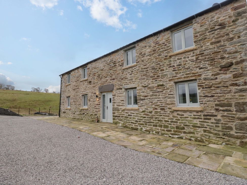 An outdoor view of a stone building with windows and a pathway at New Barn Conversion in Sedbergh