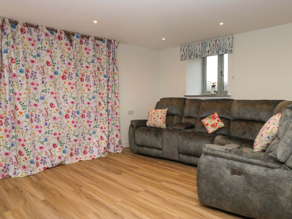 A living room with a sofa and floral curtains at New Barn Conversion in Sedbergh