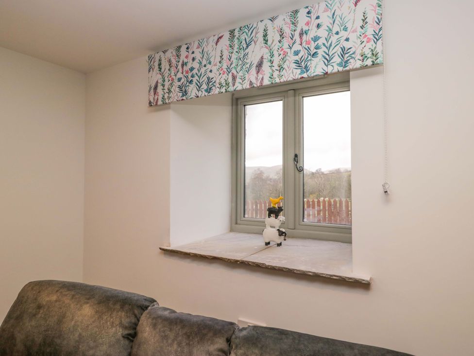 A living room with a window and decorative fabric at New Barn Conversion in Sedbergh