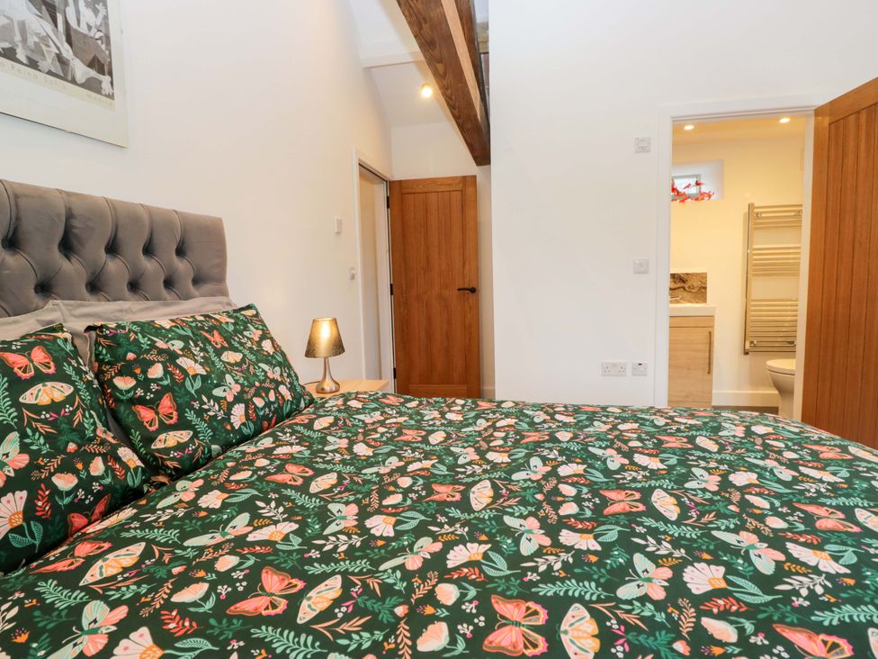 A bedroom with a bed and an open door leading to a bathroom at New Barn Conversion in Sedbergh