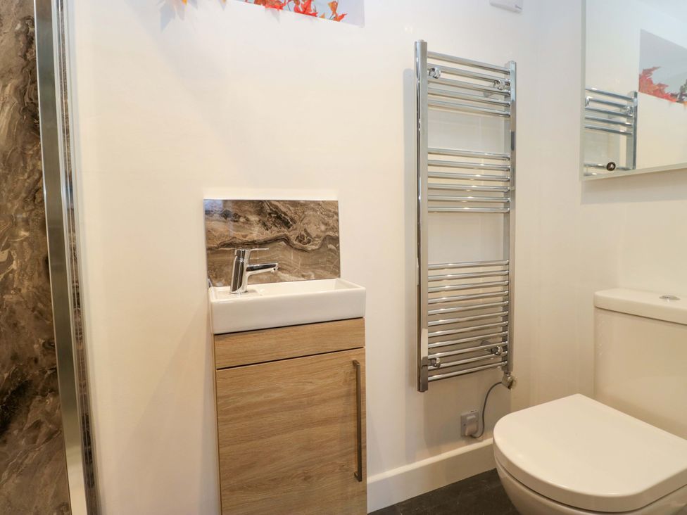A bathroom with a sink, toilet, and towel radiator at New Barn Conversion in Sedbergh