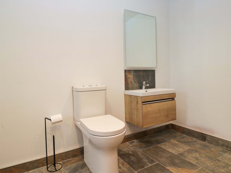 A bathroom with toilet, sink, and mirror at New Barn Conversion in Sedbergh