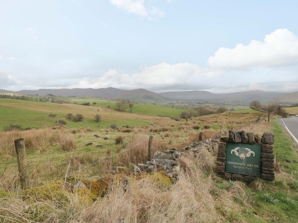 A landscape view with a sign for Yorkshire Dales National Park near a road