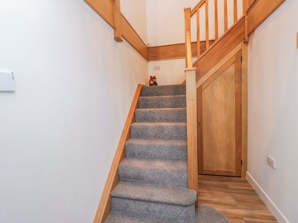 A staircase with wooden handrail and door at High Birks Barn Cautley near Sedbergh