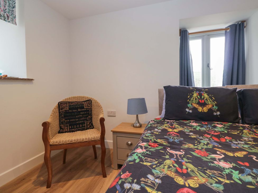 A bedroom with a bed, a chair, and a lamp at High Birks Barn in Cautley near Sedbergh