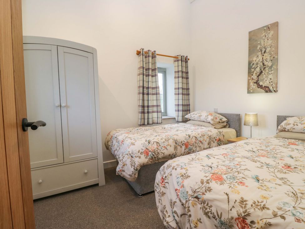 A bedroom with two beds and a wardrobe at High Birks Barn in Cautley near Sedbergh