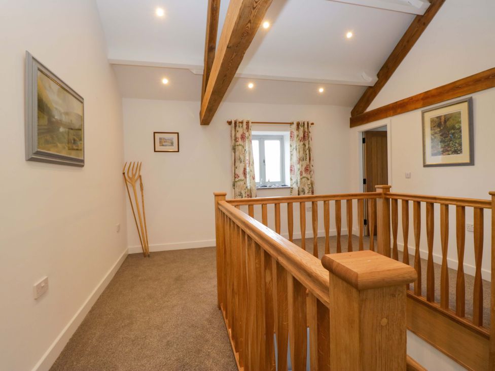 A hallway with a wooden railing and paintings at High Birks Barn Cautley near Sedbergh