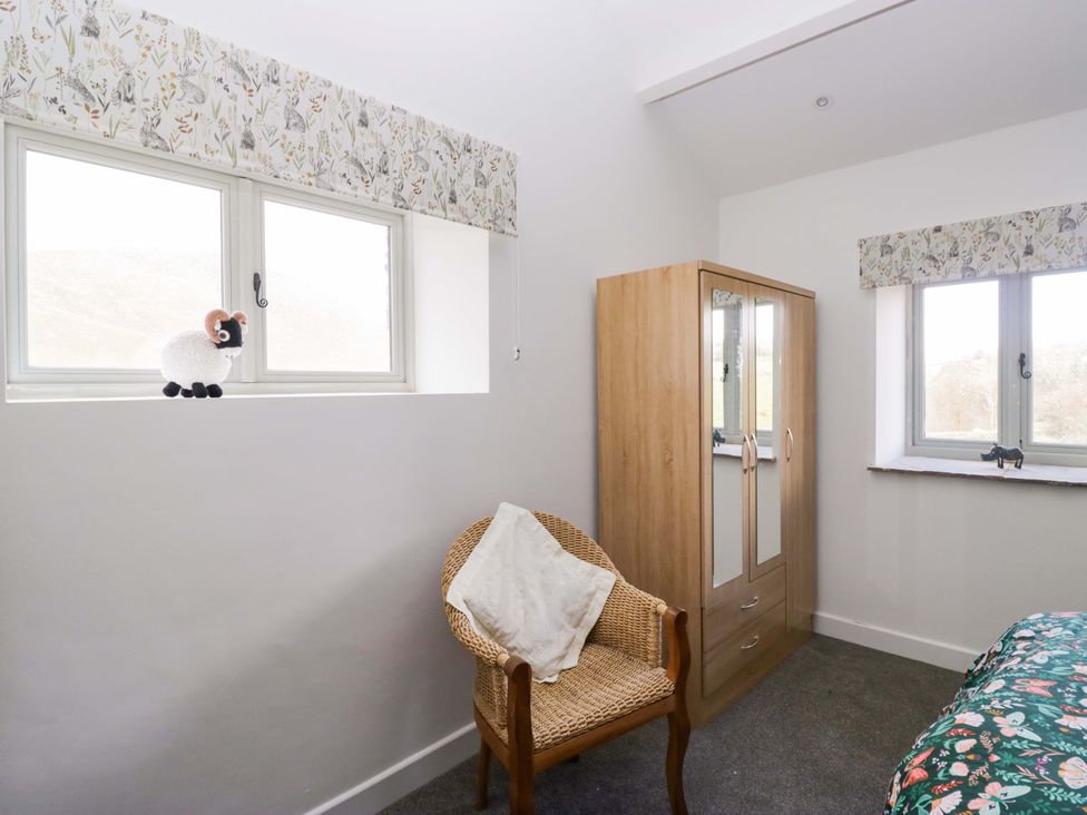 A bedroom with a wardrobe and chair at High Birks Barn in Cautley near Sedbergh