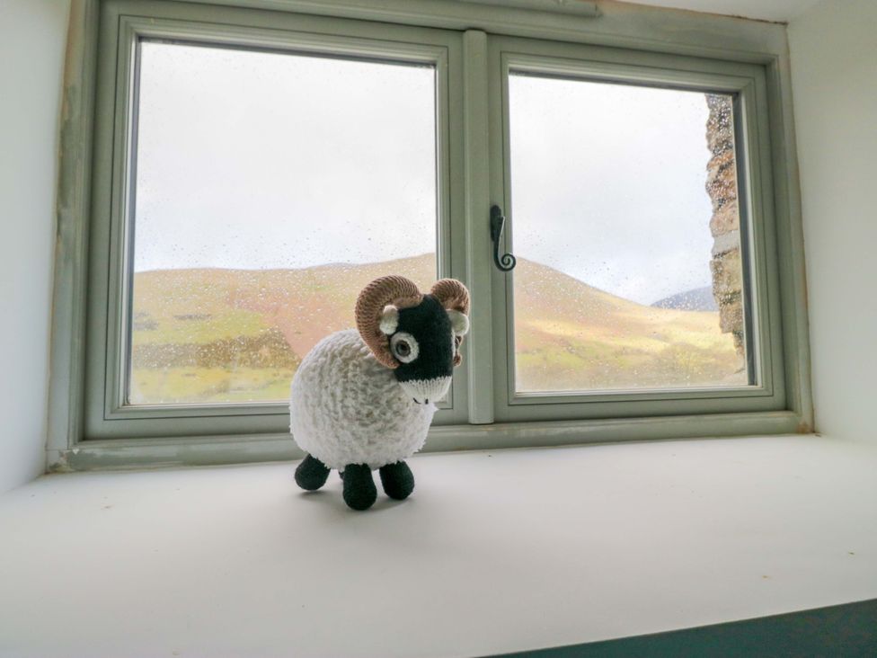 A toy sheep on a windowsill with mountains visible through the window at High Birks Barn Cautley near Sedbergh