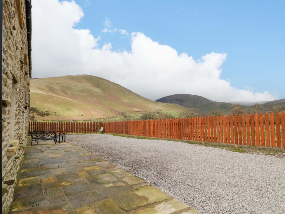 A gravel driveway next to a stone wall and wooden fence at High Birks Barn Cautley near Sedbergh