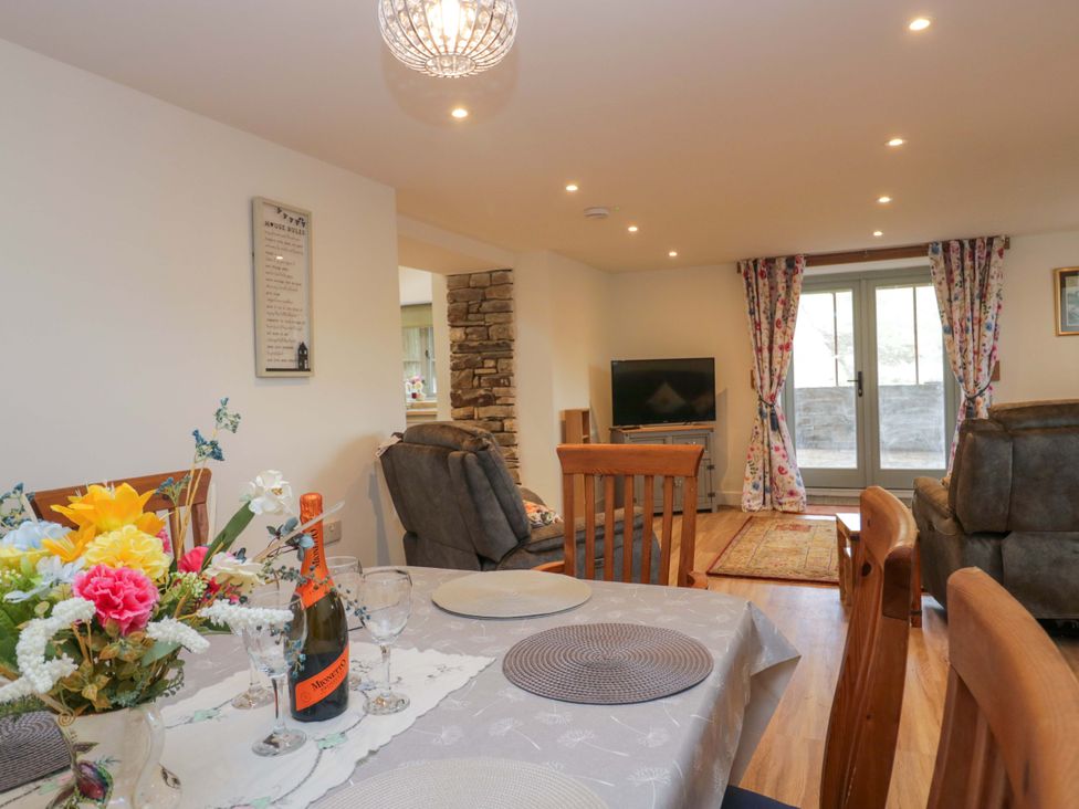 A dining room with a table set and a television at High Birks Barn in Cautley near Sedbergh