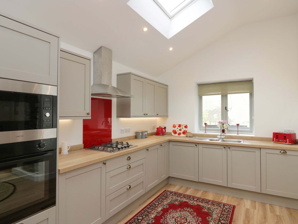 A kitchen with a stove, oven, sink, and window at High Birks Barn Cautley near Sedbergh