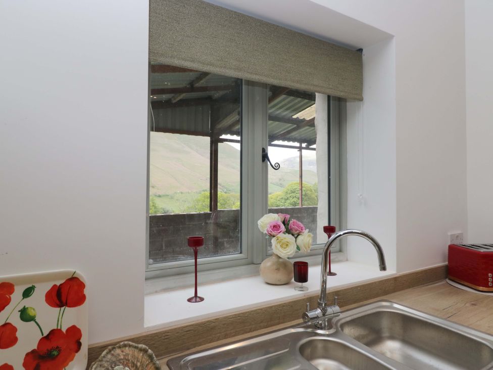 A kitchen sink with a view and flowers in a vase at High Birks Barn Cautley near Sedbergh