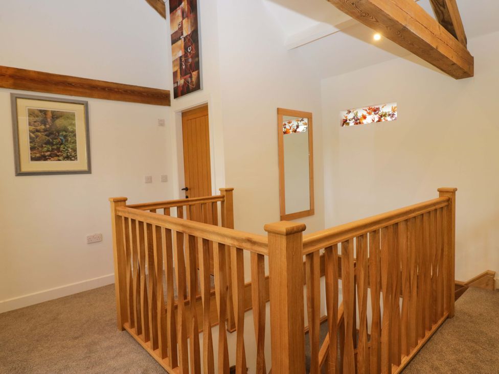 A landing with a wooden railing and a mirror at High Birks Barn Cautley near Sedbergh