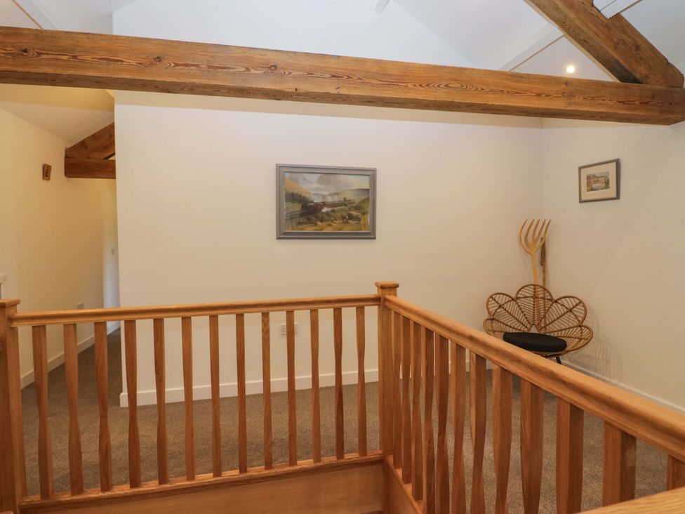 A landing with a painting and a rattan chair at High Birks Barn Cautley near Sedbergh