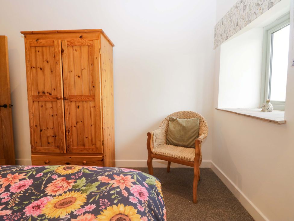 A bedroom with a wardrobe and chair at High Birks Barn in Cautley near Sedbergh