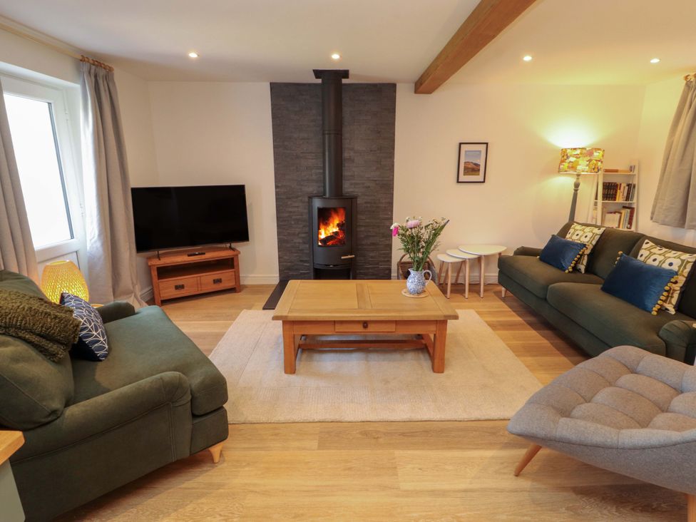 A living room with a TV and a fireplace at Bramble Cottage Thornthwaite near Braithwaite
