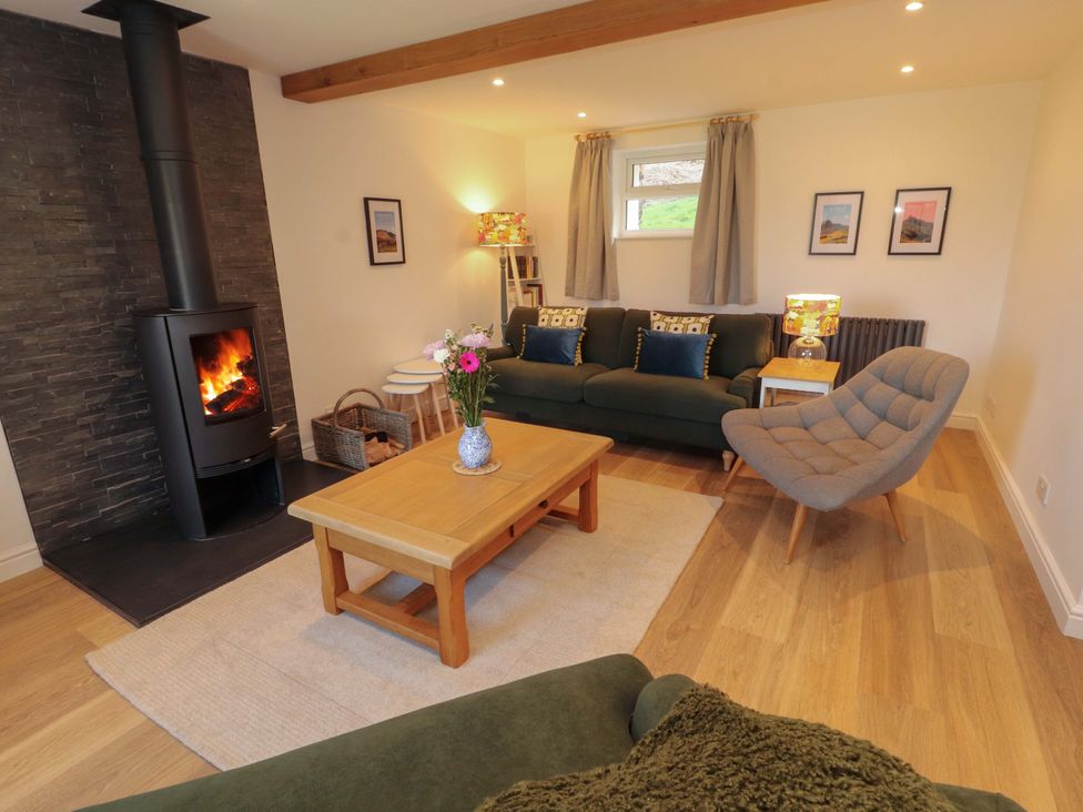A living room with a fireplace and sofa at Bramble Cottage Thornthwaite near Braithwaite