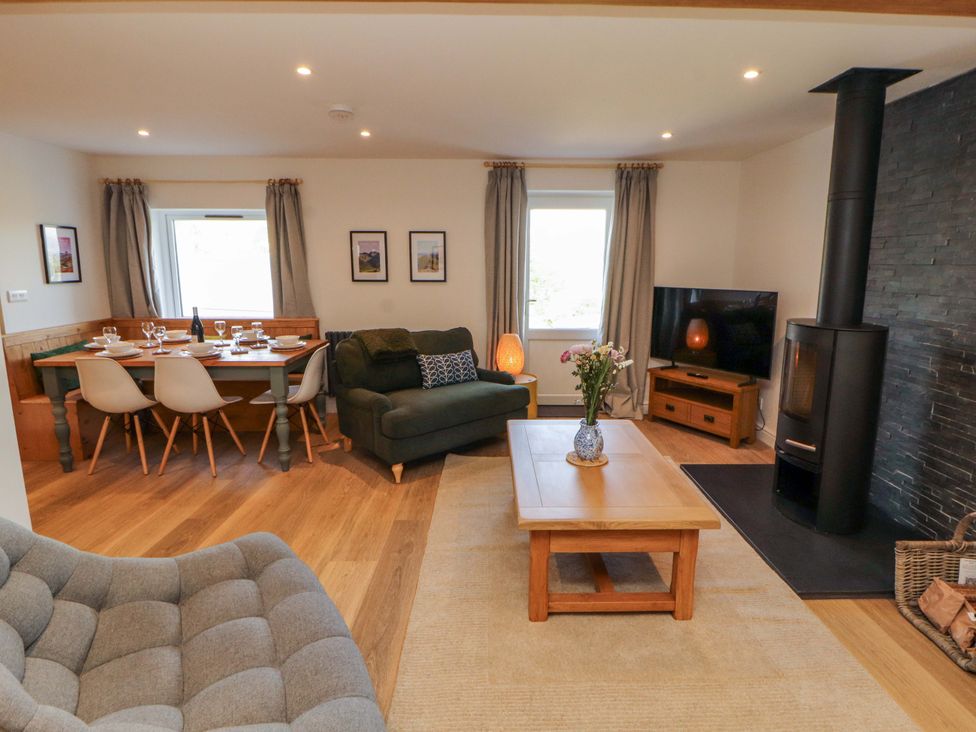 A living room with a sofa, dining table, and television at Bramble Cottage in Thornthwaite near Braithwaite