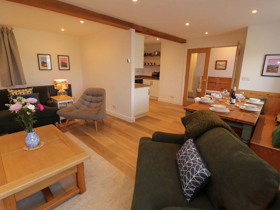 A living room with a dining area and kitchen view at Bramble Cottage in Thornthwaite near Braithwaite