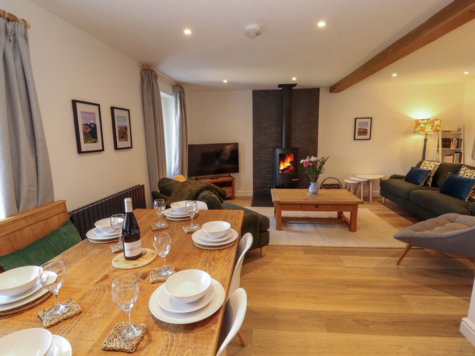 A living room with a dining area and fireplace at Bramble Cottage Thornthwaite near Braithwaite