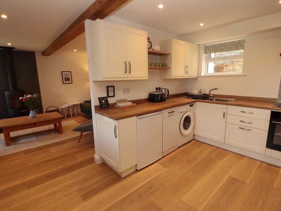 A kitchen with appliances and a table at Bramble Cottage in Thornthwaite near Braithwaite