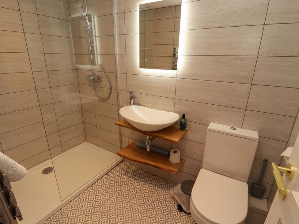 A bathroom with a shower, sink, and toilet at Bramble Cottage in Thornthwaite near Braithwaite