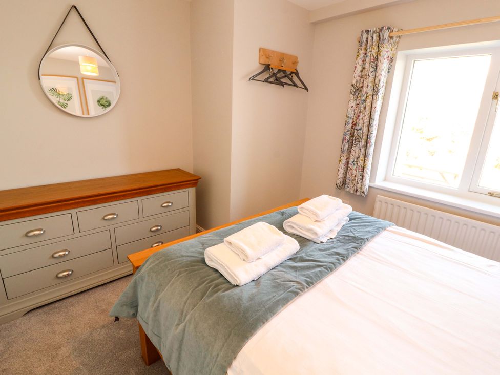 A bedroom with a bed, dresser, and mirror at Bramble Cottage Thornthwaite near Braithwaite
