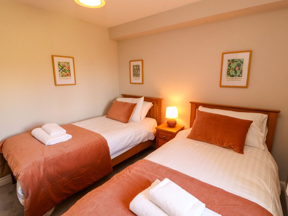 A bedroom with two beds and bedside table at Bramble Cottage Thornthwaite near Braithwaite