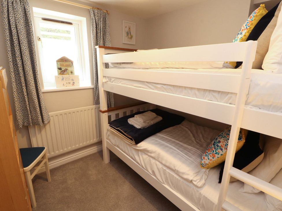 A bedroom with a bunk bed and a chair at Bramble Cottage Thornthwaite near Braithwaite