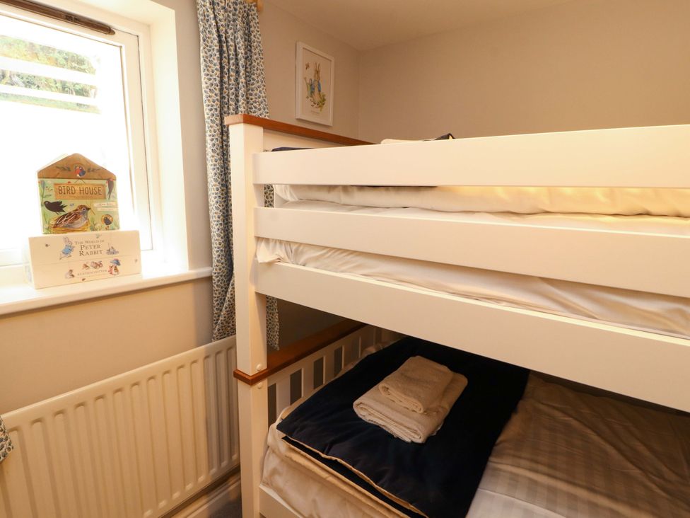 A bunk bed with towels and books at Bramble Cottage Thornthwaite near Braithwaite
