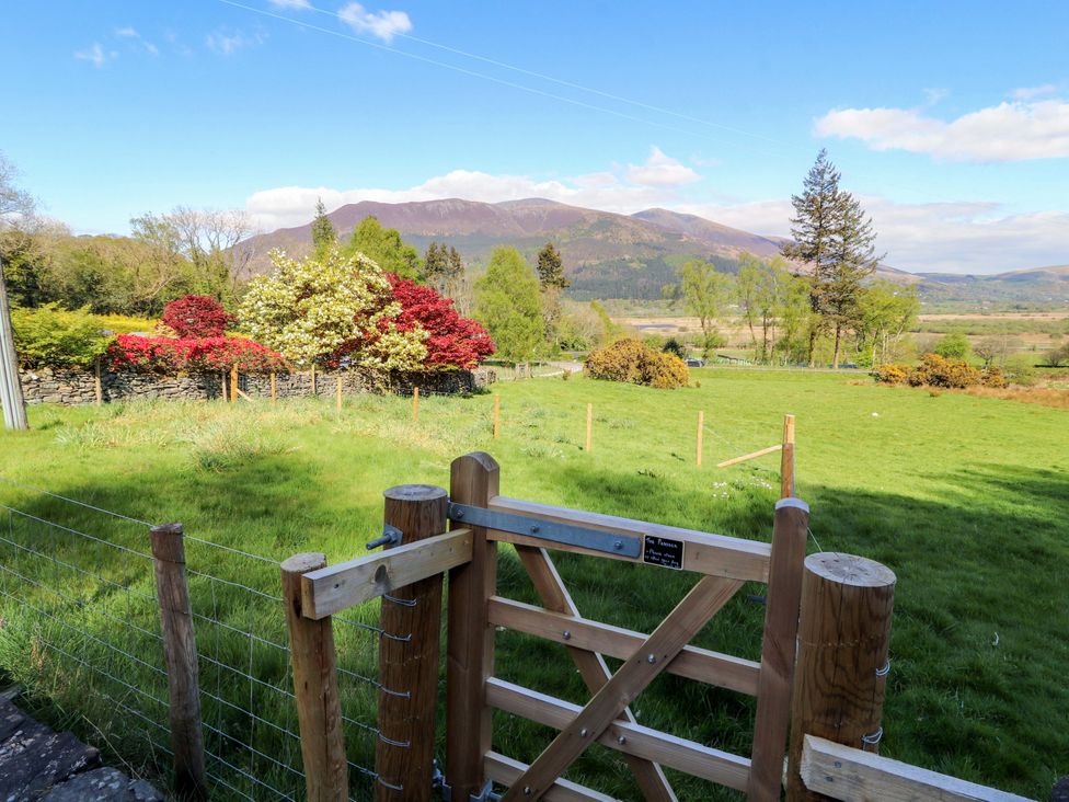 A view of a garden gate leading to a field with mountains in the background at Bramble Cottage Thornthwaite near Braithwaite