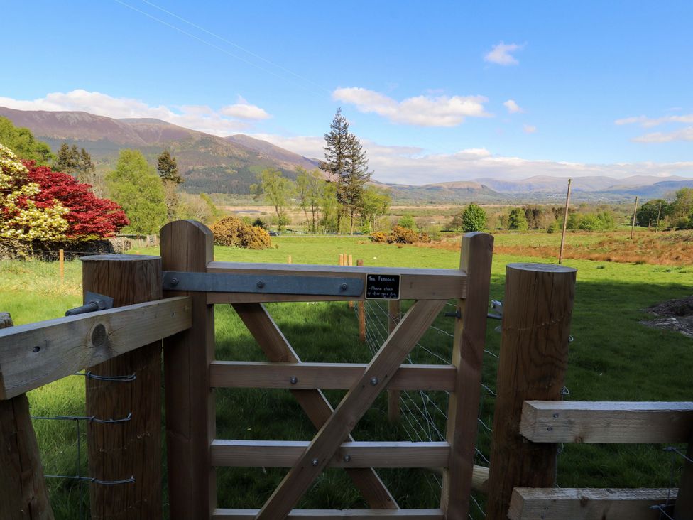 A gate opening to a field with mountains in the background at Bramble Cottage Thornthwaite near Braithwaite