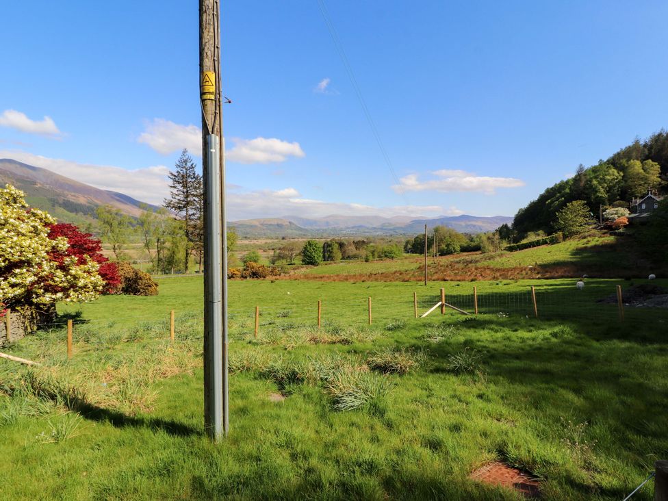 A view of grass and trees with a mountain backdrop at Bramble Cottage Thornthwaite near Braithwaite