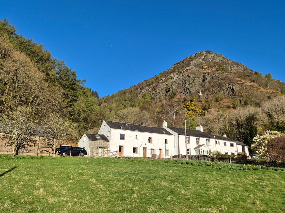 A building with a car in front and a mountain in the background at Bramble Cottage Thornthwaite near Braithwaite