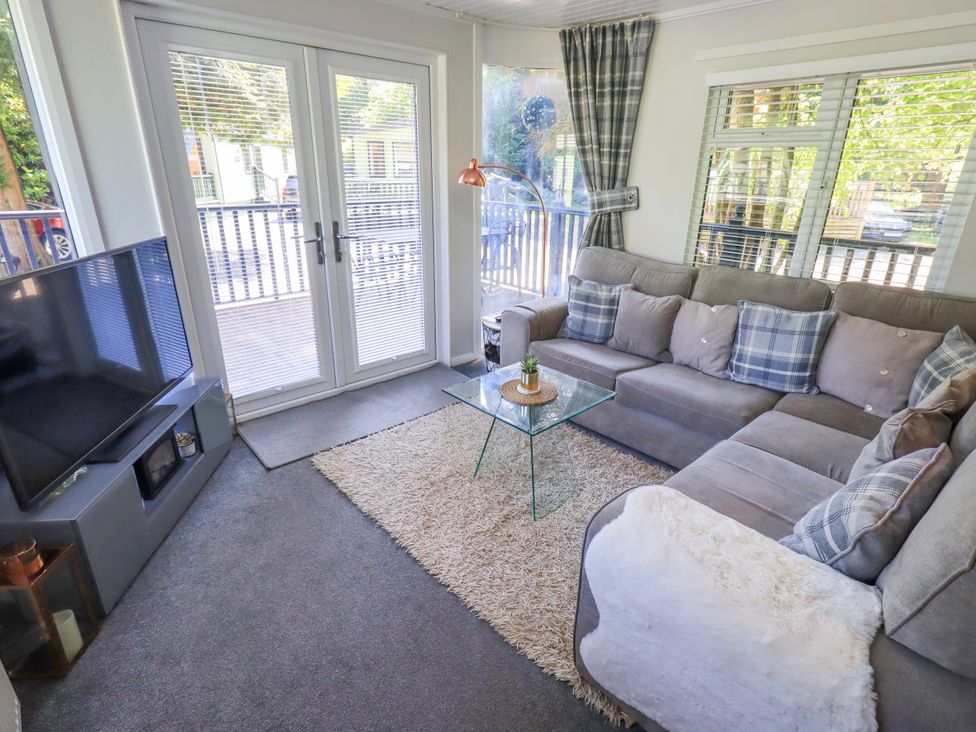 A living room with a television and sofa at Evermore Lodge 48 Calgarth Park, White Cross Bay, Windermere