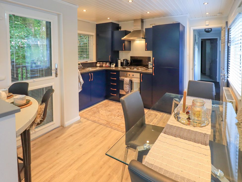 A kitchen with blue cabinets and dining table at Evermore Lodge, 48 Calgarth Park, White Cross Bay, Windermere