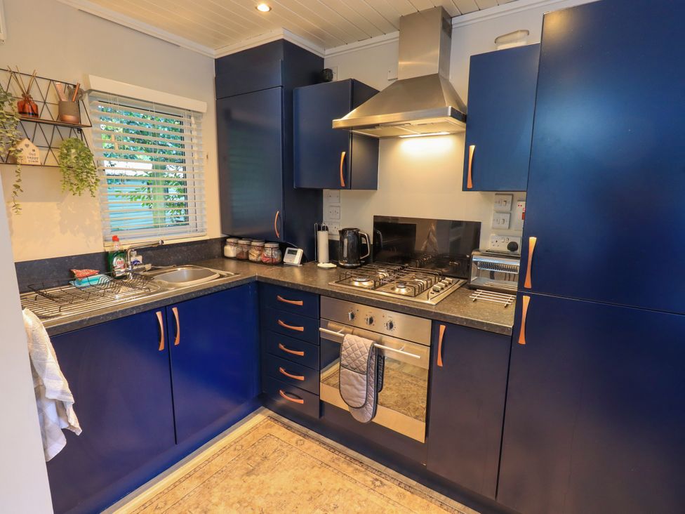A kitchen with cabinets, countertop, sink, and cooking appliances at Evermore Lodge, 48 Calgarth Park, White Cross Bay, Windermere