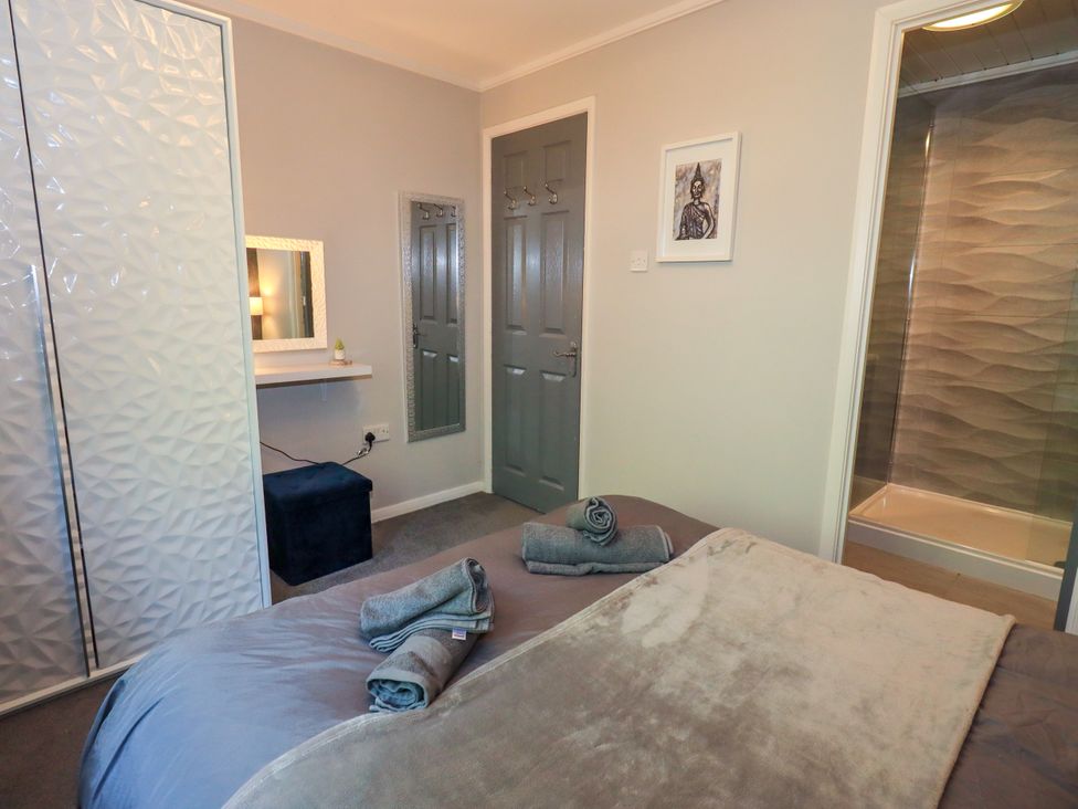 A bedroom with a bed and a dressing table at Evermore Lodge, 48 Calgarth Park, White Cross Bay, Windermere