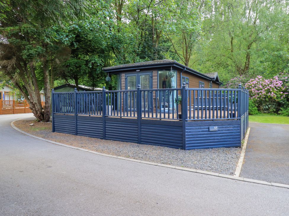 A cabin with a decking area surrounded by trees at Evermore Lodge, 48 Calgarth Park, White Cross Bay, Windermere