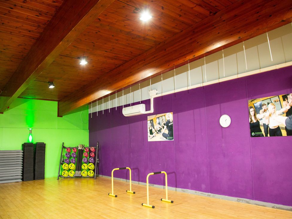 A gym with exercise mats, weights, and a clock at Evermore Lodge, 48 Calgarth Park, White Cross Bay, Windermere