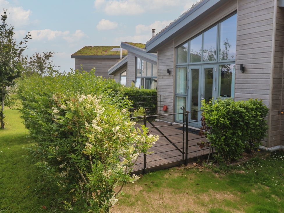 An outdoor area with a wooden deck and surrounding bushes at Una, Lodge 70 Carbis Bay